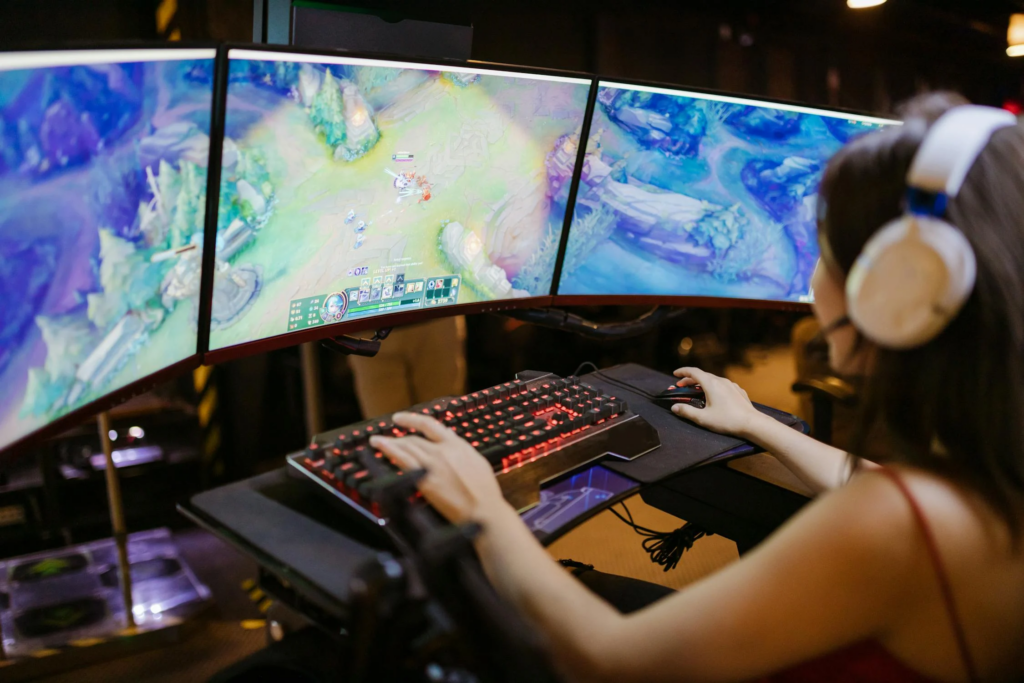 Une jeune femme jouant à un jeu vidéo sur un ordinateur avec un setup de gaming moderne.