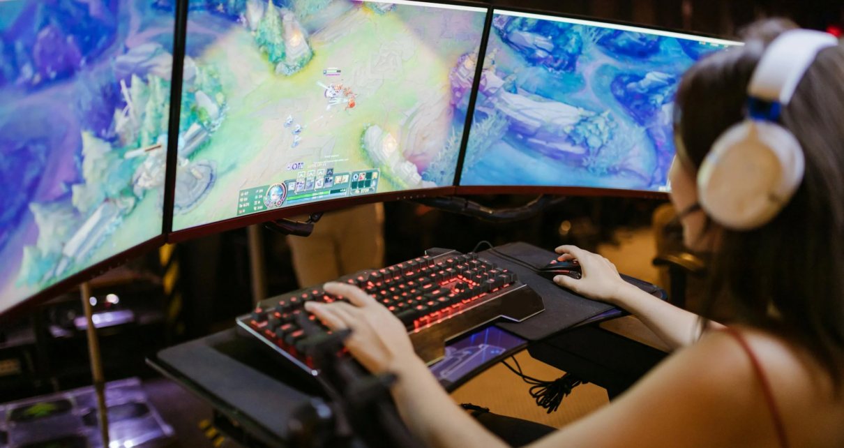 Une jeune femme jouant à un jeu vidéo sur un ordinateur avec un setup de gaming moderne.